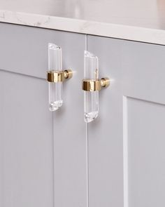 two clear glass door handles on a white cabinet