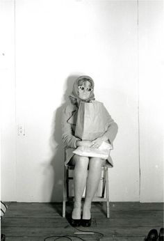 a black and white photo of a woman sitting on a chair holding a paper bag