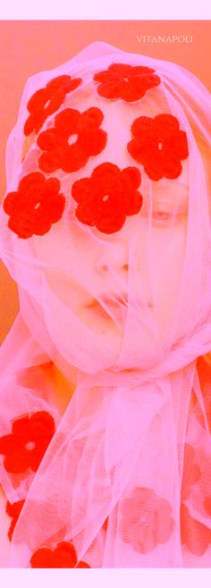 a woman wearing a veil with red flowers on it