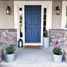 a blue front door with two planters and an american flag