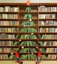 two elfs standing in front of a bookshelf with christmas decorations on it