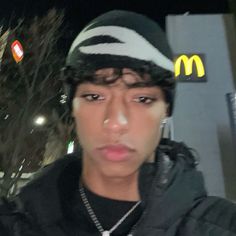 a young man wearing a hat and jacket in front of a mcdonald's sign