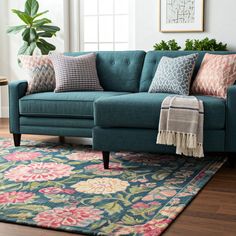 a blue couch sitting on top of a wooden floor next to a green chair and rug