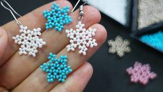 small snowflake earrings are being held in someone's hand next to other items