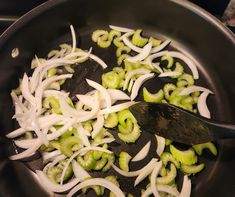 onions and broccoli being cooked in a skillet with a spatula on the side