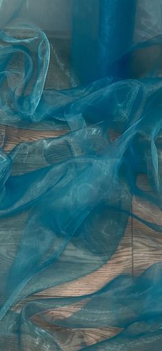 blue sheer fabric on wood flooring next to roll of thread