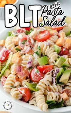 a pasta salad with tomatoes, avocado and lettuce in it on a white plate