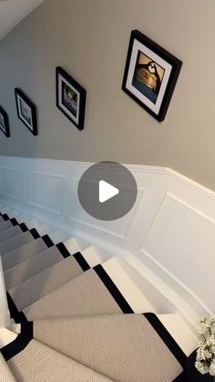 a staircase with pictures on the wall and carpeted flooring in front of it