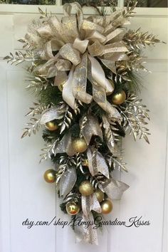 a christmas wreath hanging on the front door with gold and silver ornaments around it,