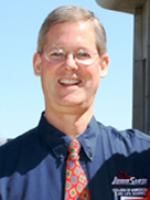 a man wearing glasses and a tie standing in front of a building