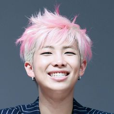 a person with pink hair smiling at the camera