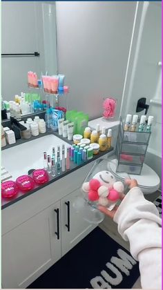 a person is holding some soaps in front of a bathroom counter with many bottles and containers on it