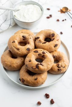 chocolate chip bagels on a white plate with raisins and cream in the background