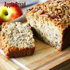 a loaf of apple bread sitting on top of a cutting board next to an apple