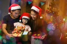 a man, woman and child opening a christmas present