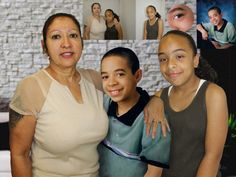 a woman and two children are posing for a photo with their family pictures in the background