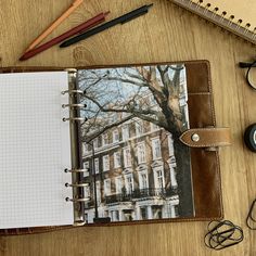 an open notebook sitting on top of a wooden table next to a pen and eyeglasses