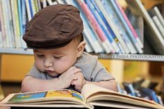 a small child reading a book in front of a bookshelf