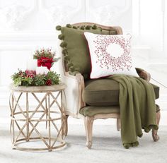 a chair with a christmas pillow on it next to a small table and potted plants