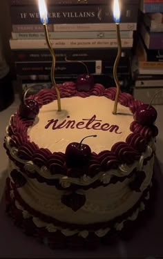 a cake with two candles on top of it and some books in the back ground