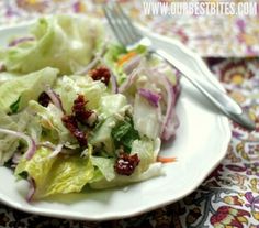 a white plate topped with lettuce and cranberry salad next to a fork