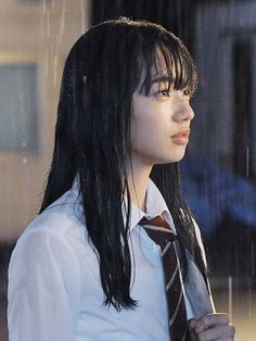 a woman with long black hair wearing a white shirt and tie standing in the rain