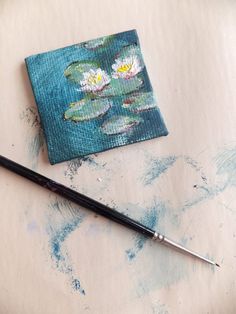 a painting with water lilies on it next to a brush