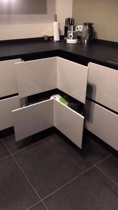 a kitchen with white cabinets and black counter tops is shown in this image, there are utensils on the left side of the cabinet