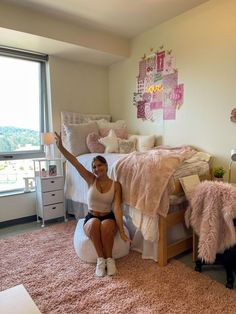 a woman sitting on top of a bed in a bedroom next to a large window