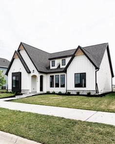 a large white house with black trim and windows on the front porch, grass in front yard