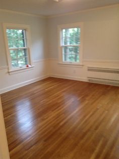 an empty room with hard wood floors and windows