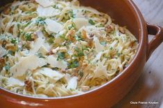 a brown bowl filled with pasta and parmesan cheese