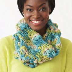 a woman wearing a multicolored crocheted cowl with a smile on her face