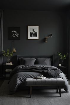 a bedroom with black walls and grey bedding, artwork on the wall above it