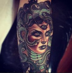 a woman's face with snakes around her head on the arm, and behind her is a snake tattoo