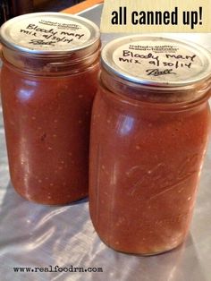 two jars filled with red sauce sitting on top of a white cloth covered tablecloth