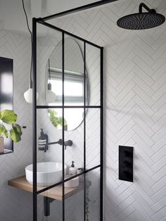 a bathroom with a glass shower door and white tiles on the walls, along with a sink