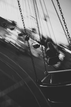 a black and white photo of a child's swing set at a carnival park