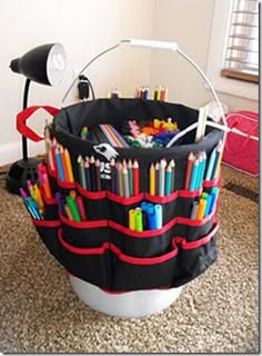 a bucket filled with lots of colored pencils on top of a carpeted floor