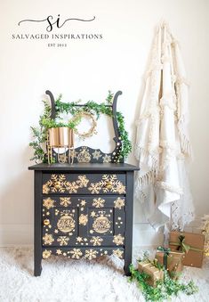 a black and gold painted dresser sitting on top of a white rug next to a christmas tree