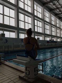 a woman in a bathing suit sitting on the edge of a swimming pool