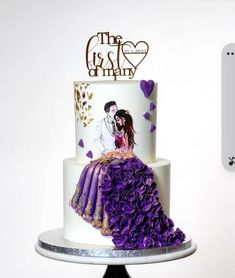 a wedding cake decorated with purple flowers and a couple on top