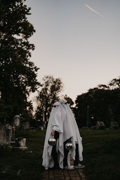 a person dressed as a ghost standing in the grass