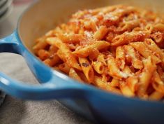 a blue pan filled with pasta on top of a table