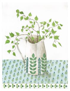 a white vase filled with green leaves on top of a blue and white table cloth