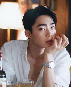 a young man sitting at a table with two glasses and bottles in front of him