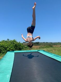 a woman is doing a handstand on a trampoline