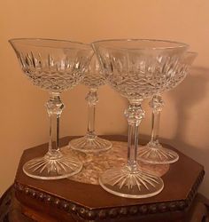 three clear wine glasses sitting on top of a wooden table next to a brown box