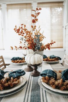 the table is set with white pumpkins, blue napkins and other fall decorations