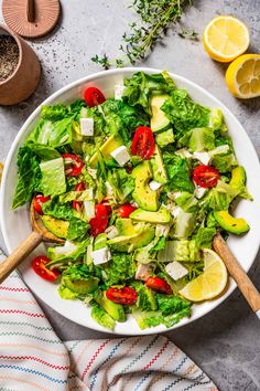 a salad with lettuce, tomatoes and cucumbers in a white bowl